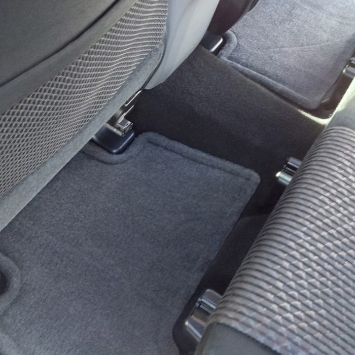 Clean car floor after dog hair removal, showing spotless carpet in the back seat area.