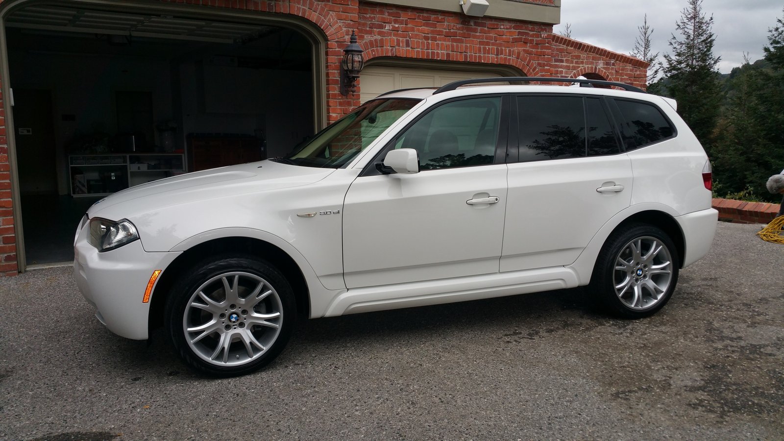 Clean white BMW SUV parked in front of a garage after a professional detailing service.