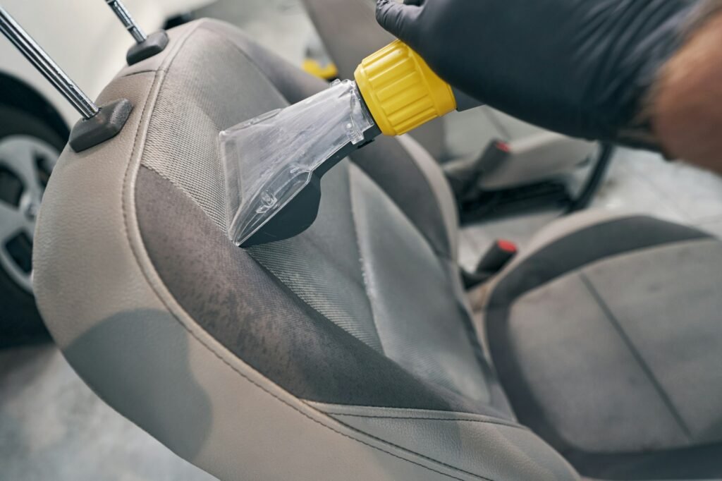 Close-up of a car seat being vacuumed during a detailing service.