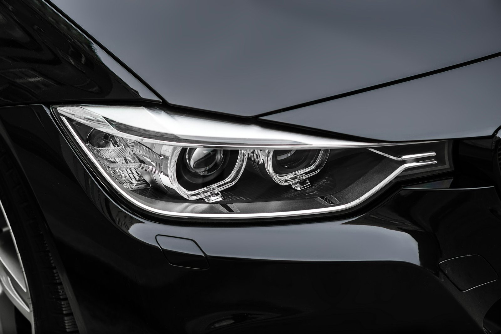 Close-up of a sleek and polished headlight on a black luxury car.