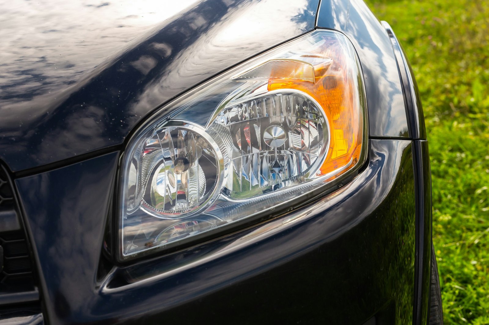 Close-up of a clean and polished car headlight on a black vehicle.