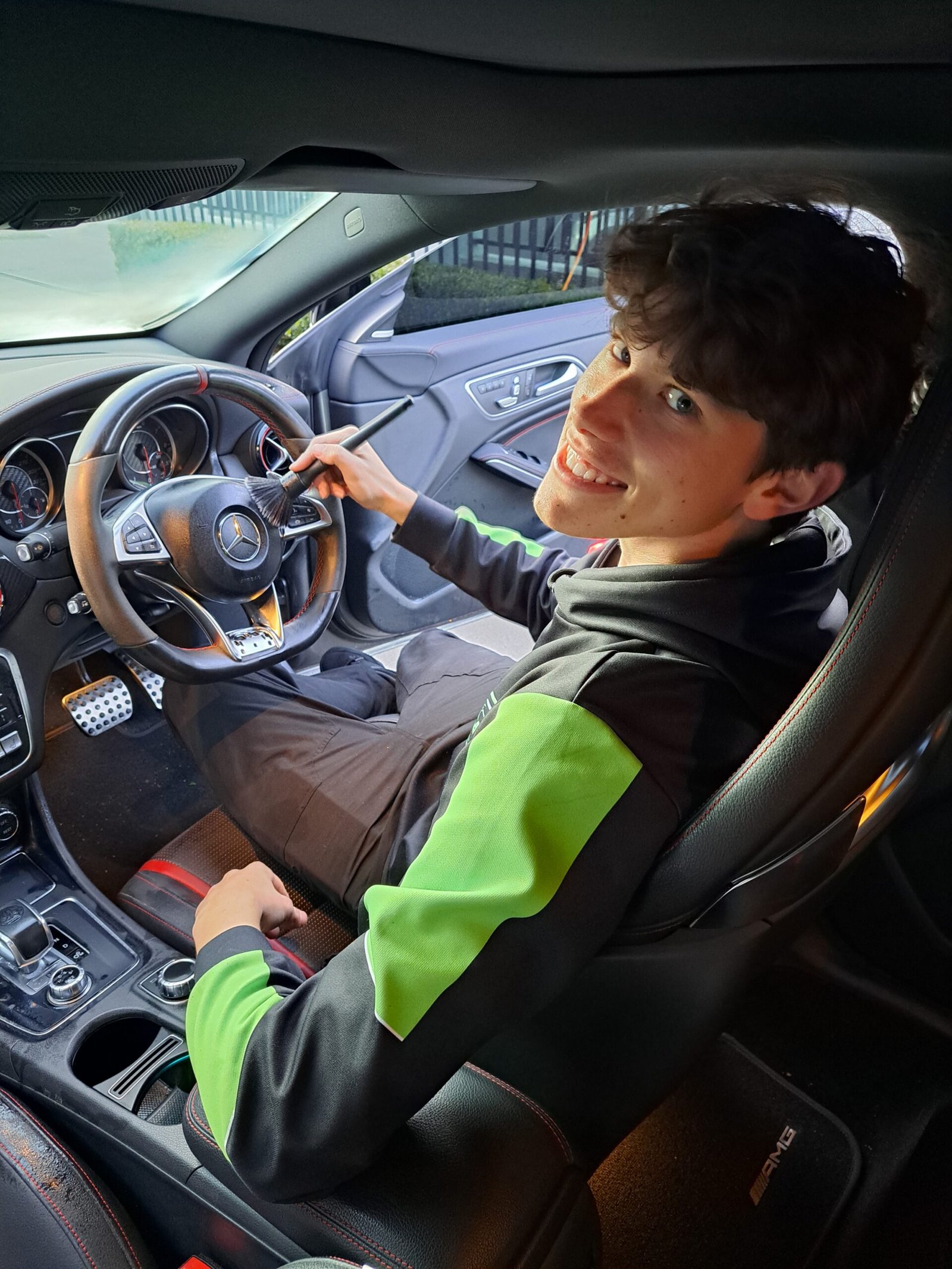 Detailer smiling while cleaning the interior of a car from the driver’s seat.