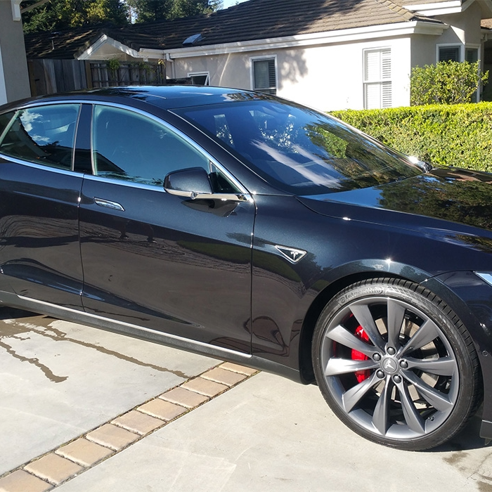 Shiny black Tesla parked on a driveway after a detailing service.