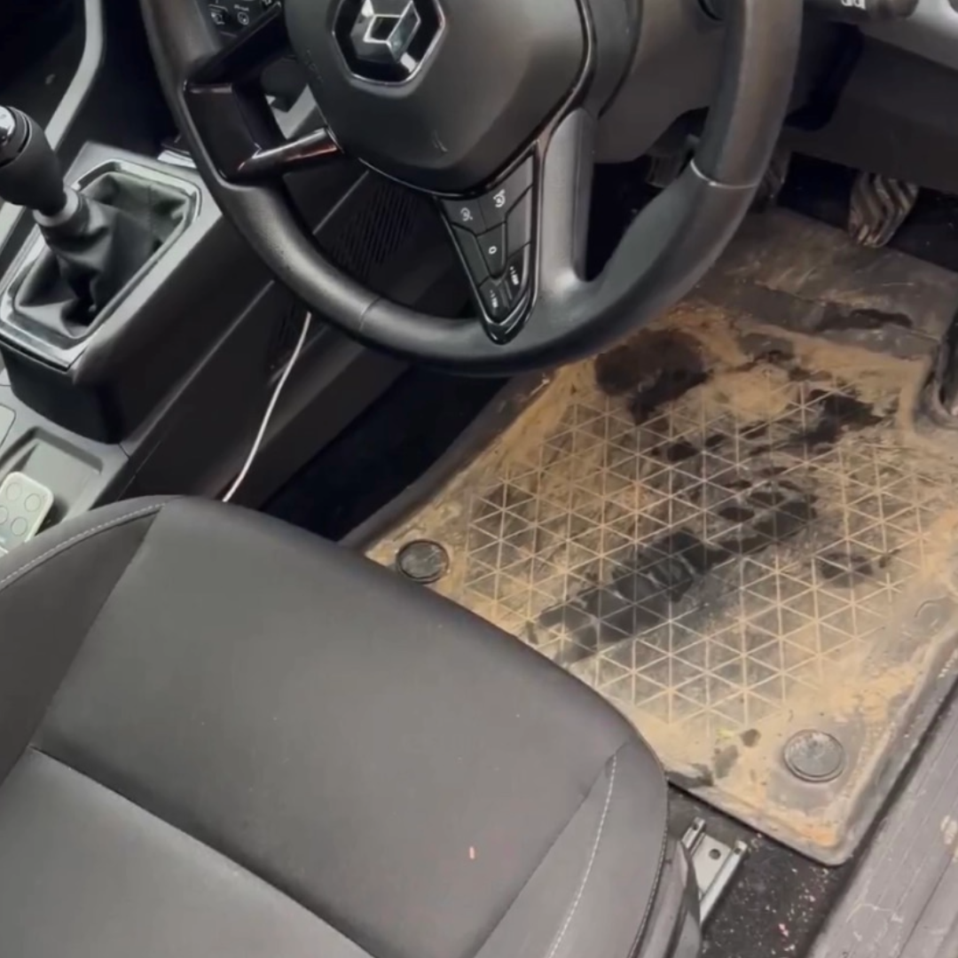 Dirty car interior showing a soiled driver’s floor mat before a detailing service.