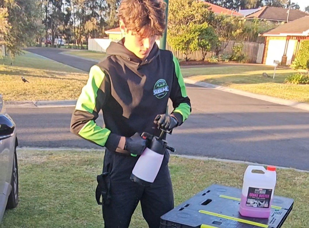 Detailer preparing foam spray equipment for car cleaning in a residential neighborhood.