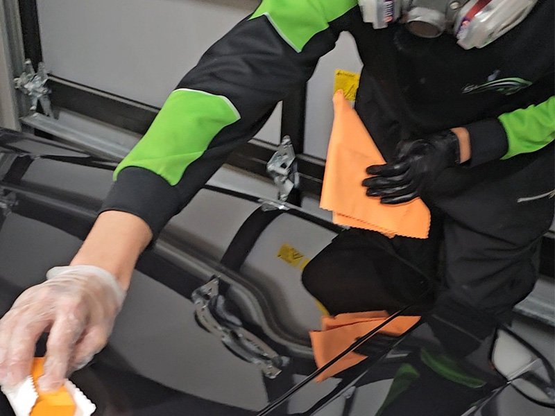 "Close-up of a car receiving a ceramic coating, highlighting the glossy, protective layer being applied to enhance shine and durability